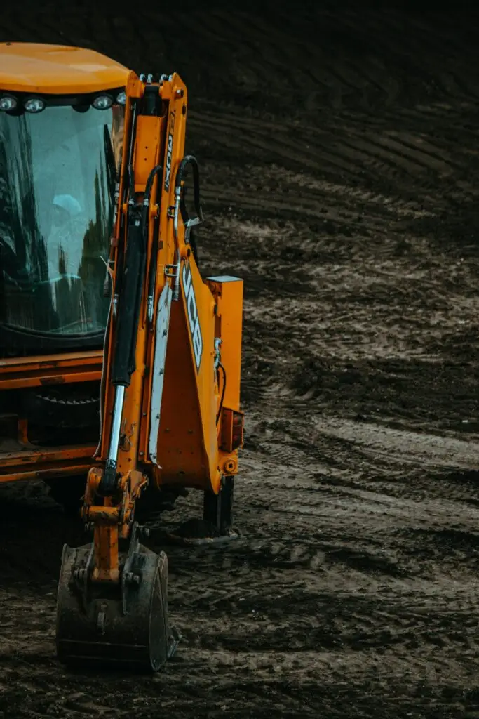 Close-up of a yellow excavator on a construction site with muddy terrain.
